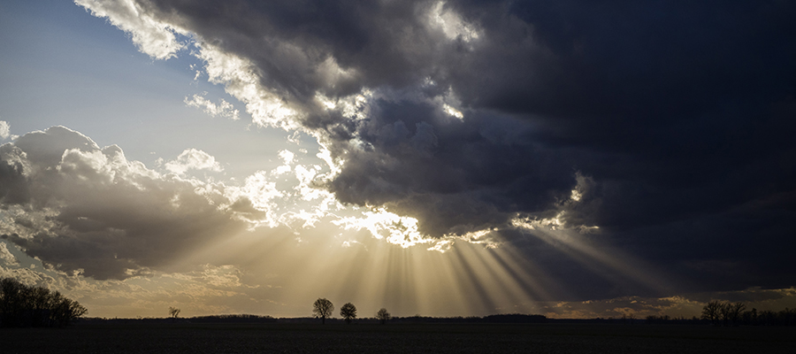 Sun rays showing from behind dark storm clouds.